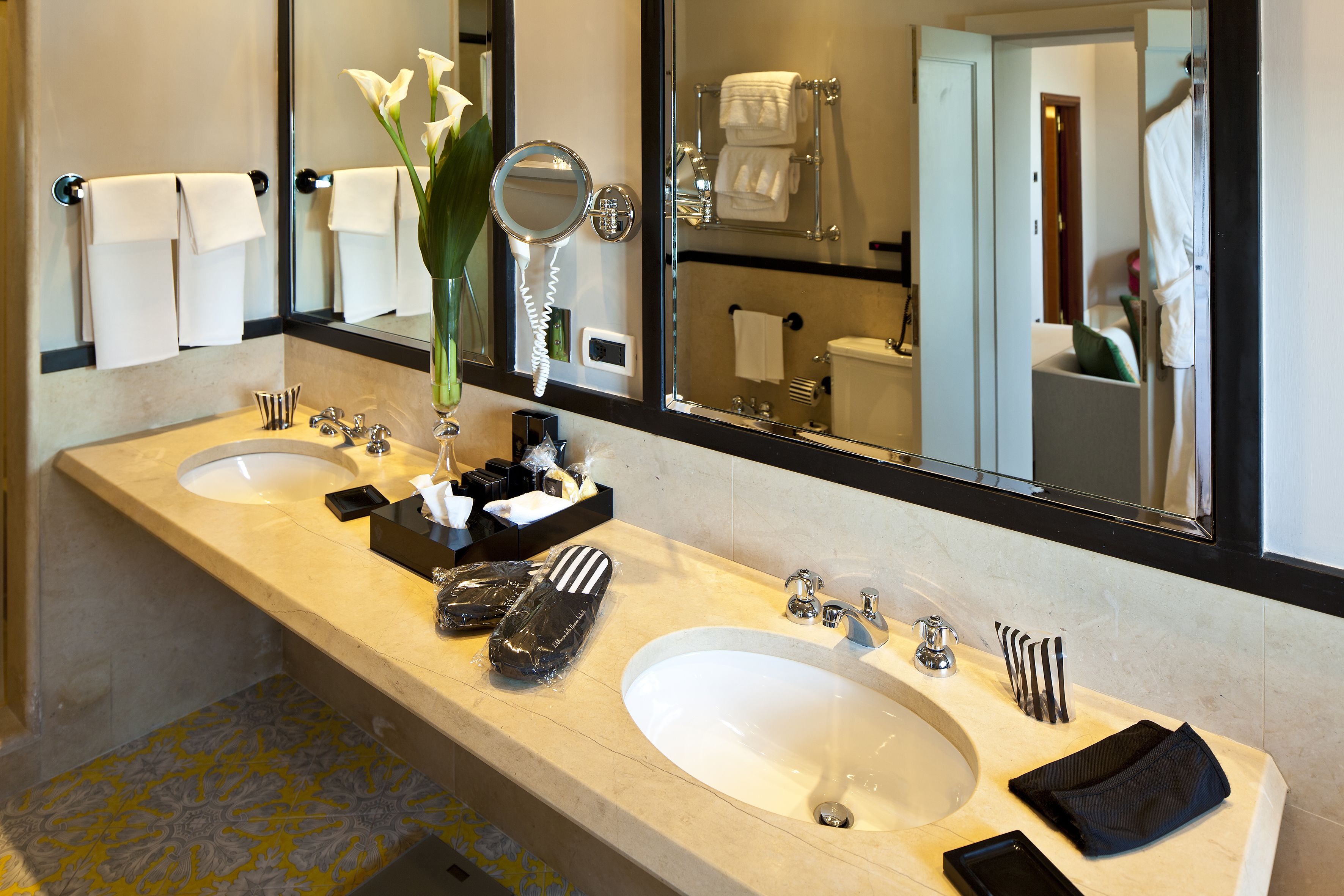 Un baño de hotel con dos lavamanos, un espejo grande y un perchero para toallas.