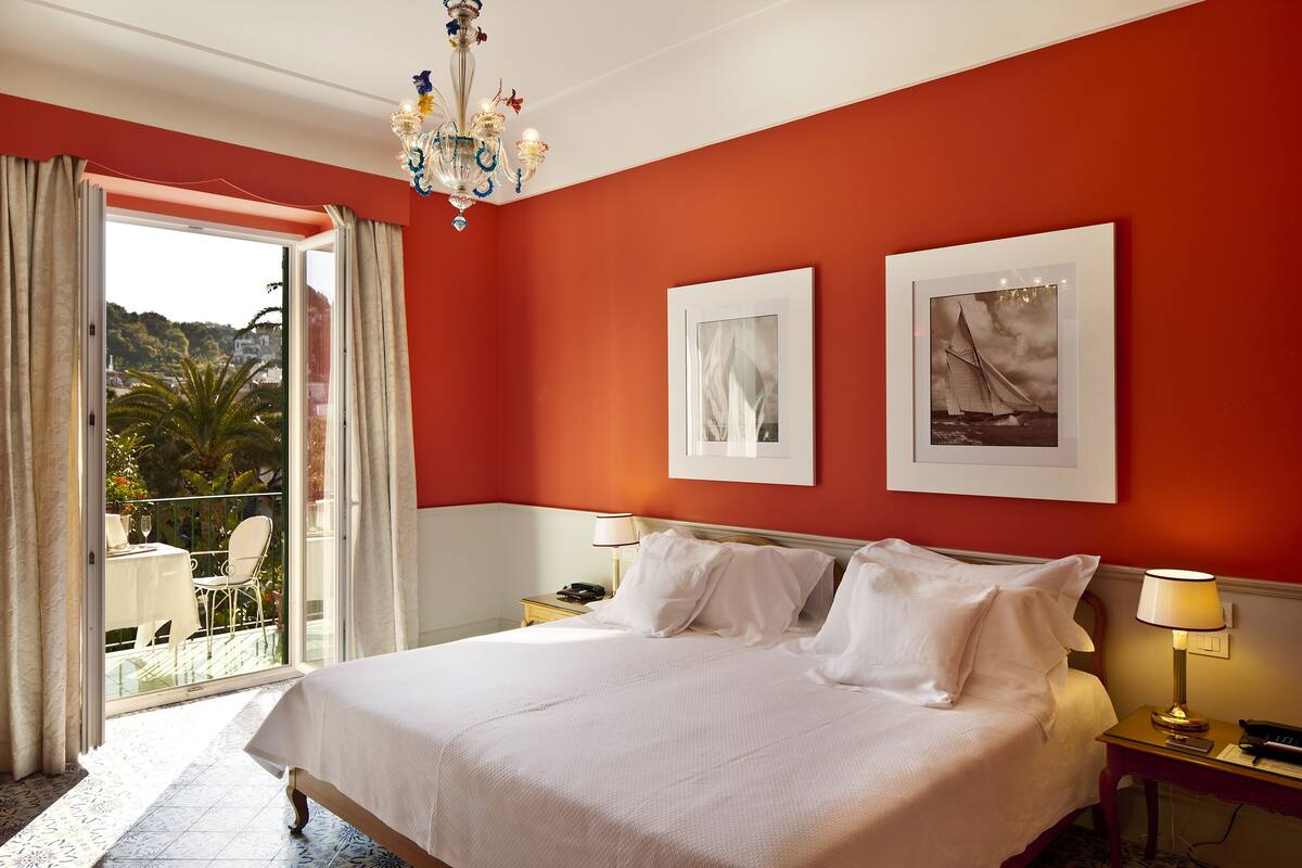Une chambre d’hôtel avec un lit, deux tables de chevet, un lustre et deux tableaux encadrés au mur.
