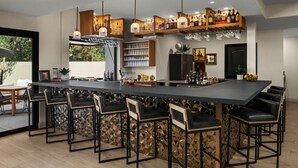 A modern kitchen with a long bar area, bar stools, and a variety of kitchen appliances.