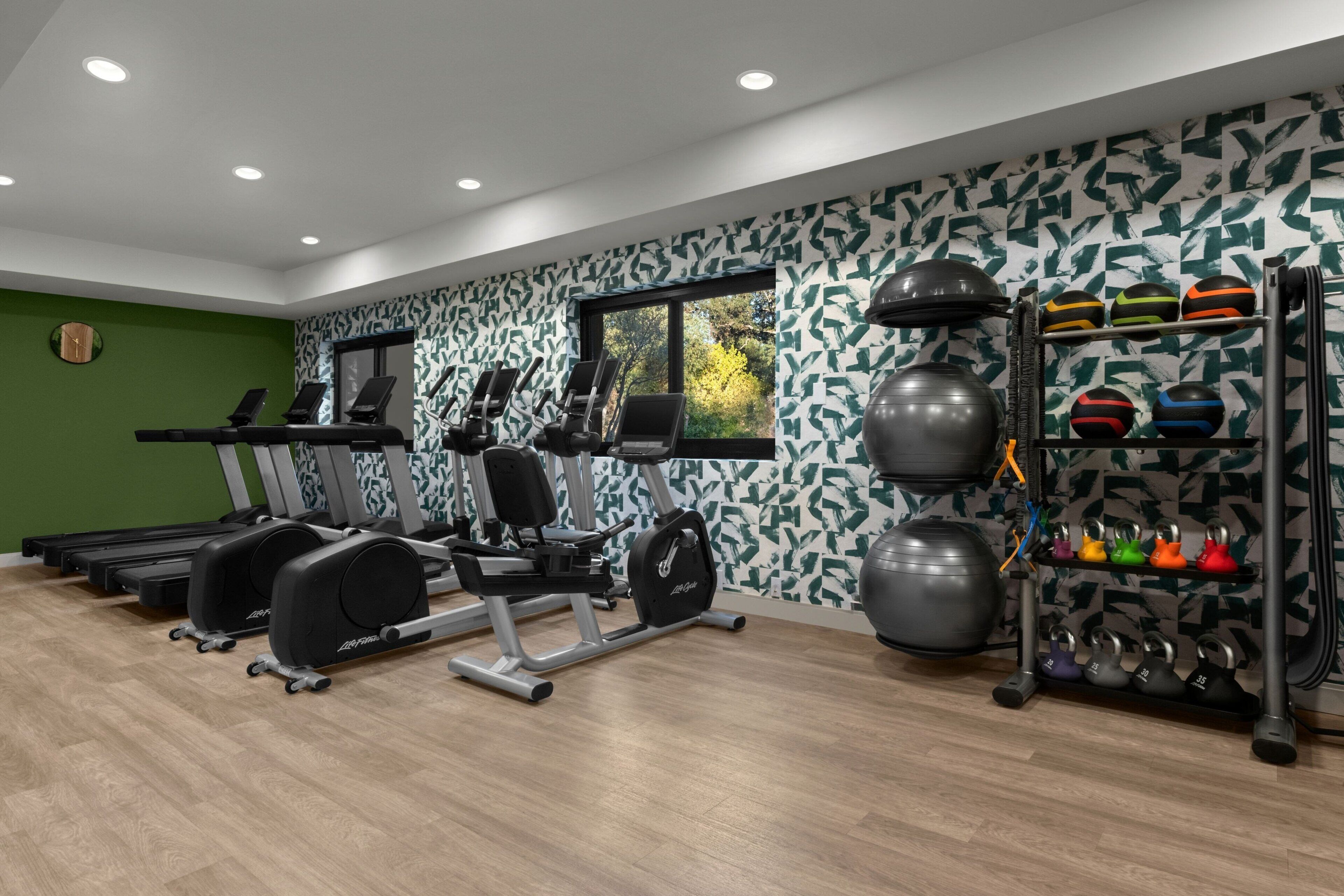 A modern gym with treadmills, weight machines, and a variety of exercise balls and dumbbells.