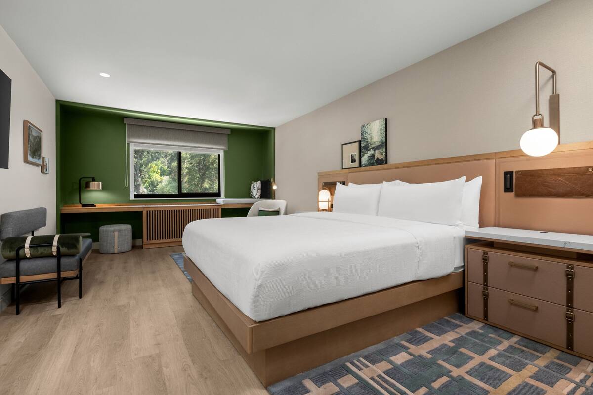 A modern hotel room with a large bed, a desk, and a chair.