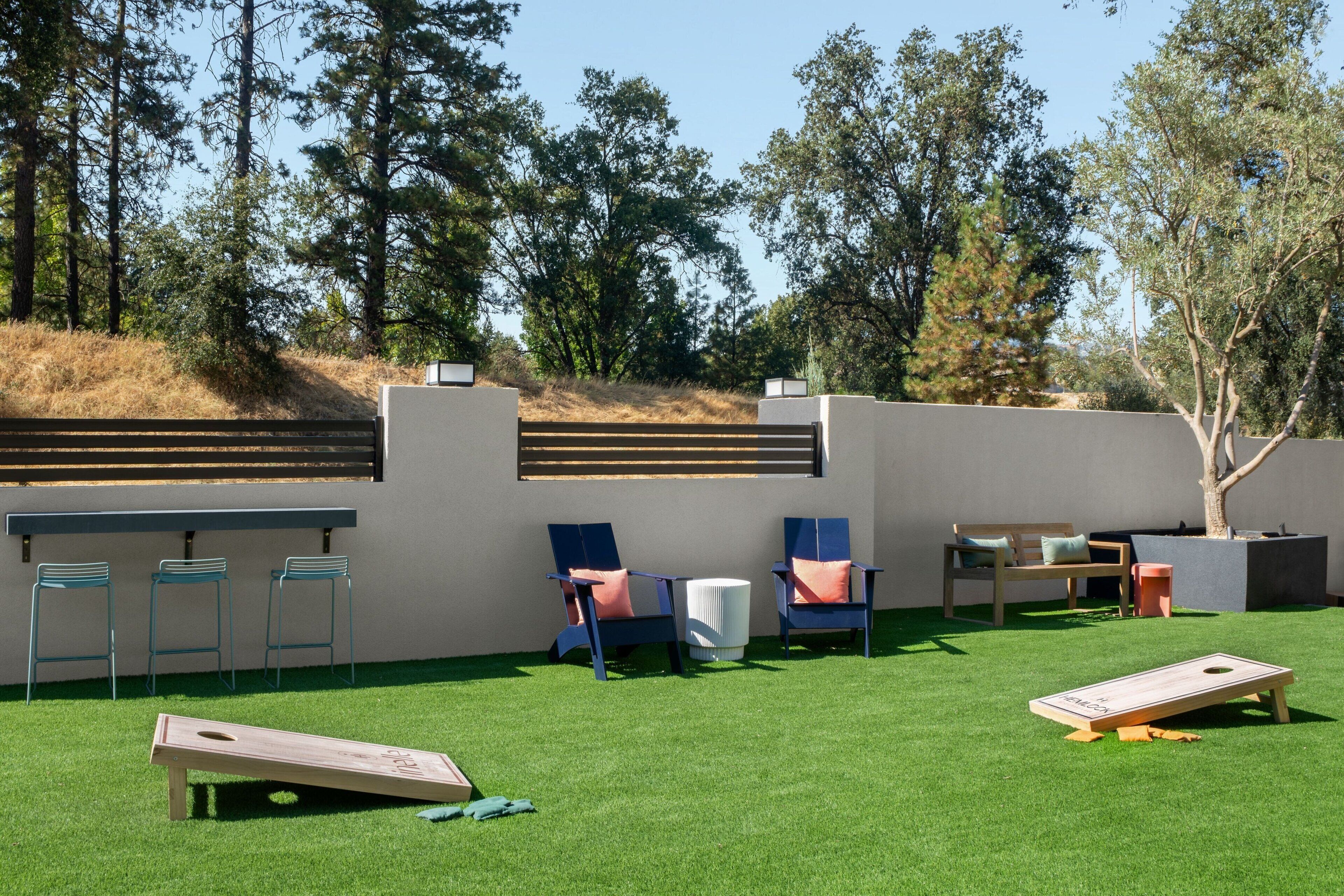 Un patio con césped artificial, una mesa de madera y varias sillas.
