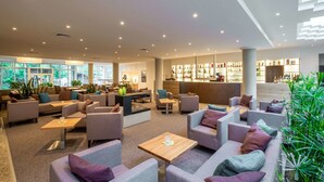 A modern lounge area with sofas, tables, and a bar. - Quality Hotel Lippstadt (Lippstadt)