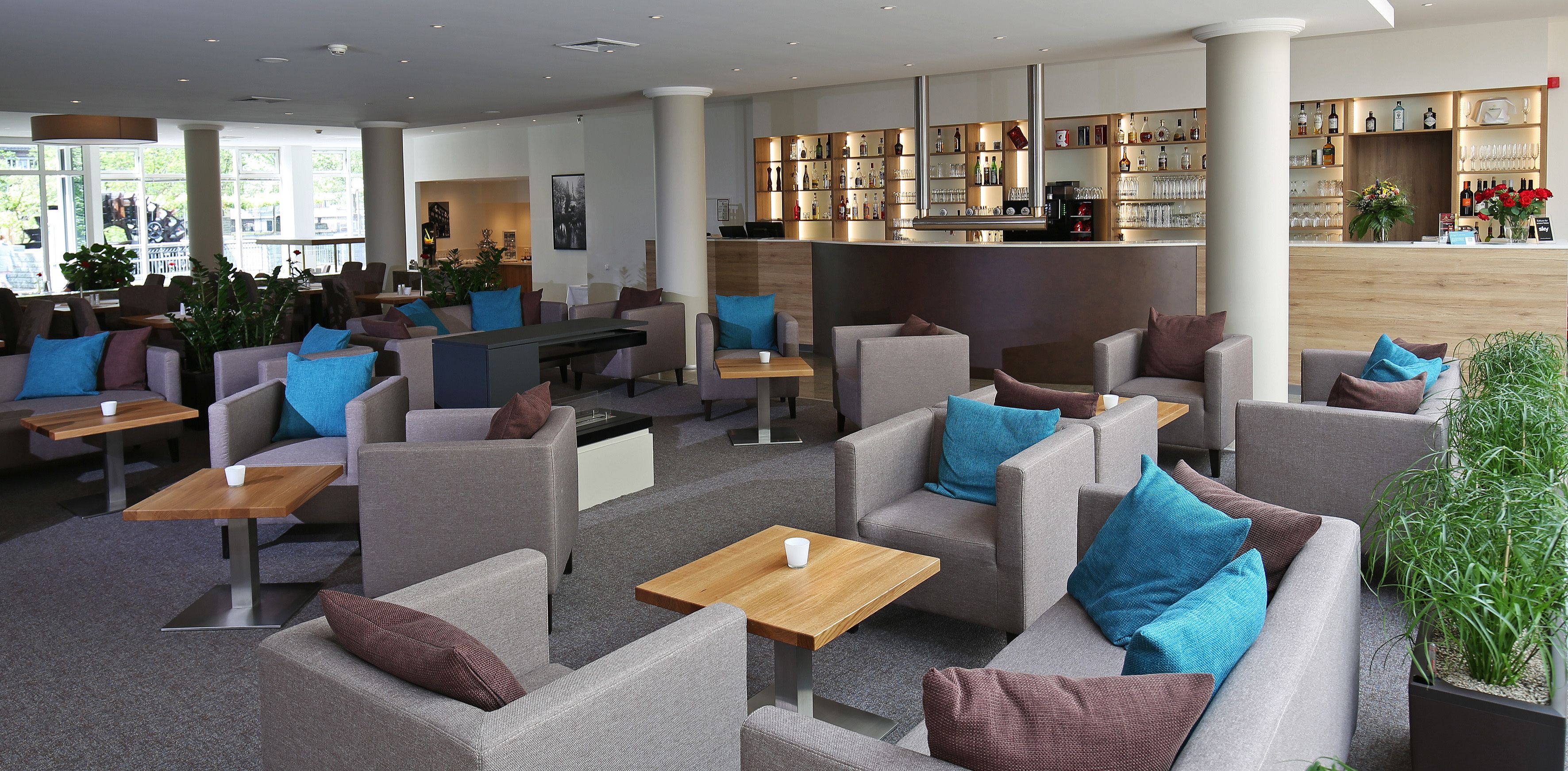 Eine moderne Hotelhalle mit Sofas, Tischen und einer Bar.