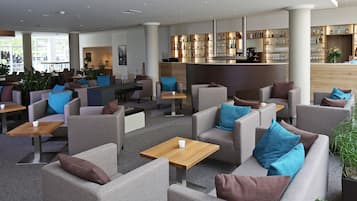 Eine moderne Hotelhalle mit Sofas, Tischen und einer Bar.
