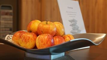 Un bol de manzanas sobre una mesa, con un mantel individual y un cartel de menú al fondo.