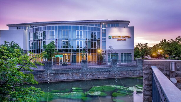 A modern hotel with a glass facade, a stone entrance, and a water feature with lily pads. - Quality Hotel Lippstadt (Lippstadt)