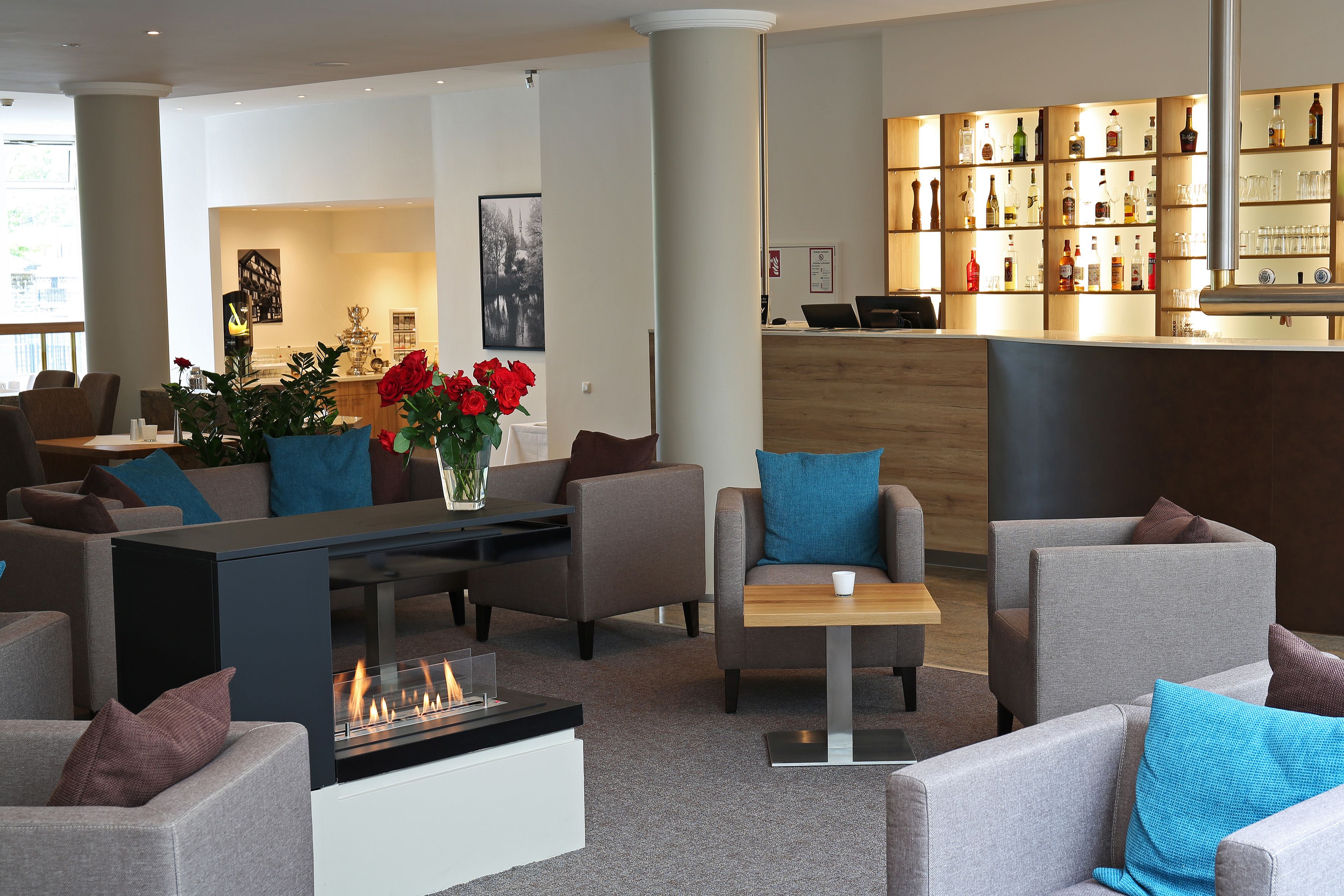 A modern hotel lobby with a reception desk, seating area, and a fireplace.