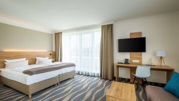 Ein Hotelzimmer mit Bett, Schreibtisch, Fernseher und einer Couch.