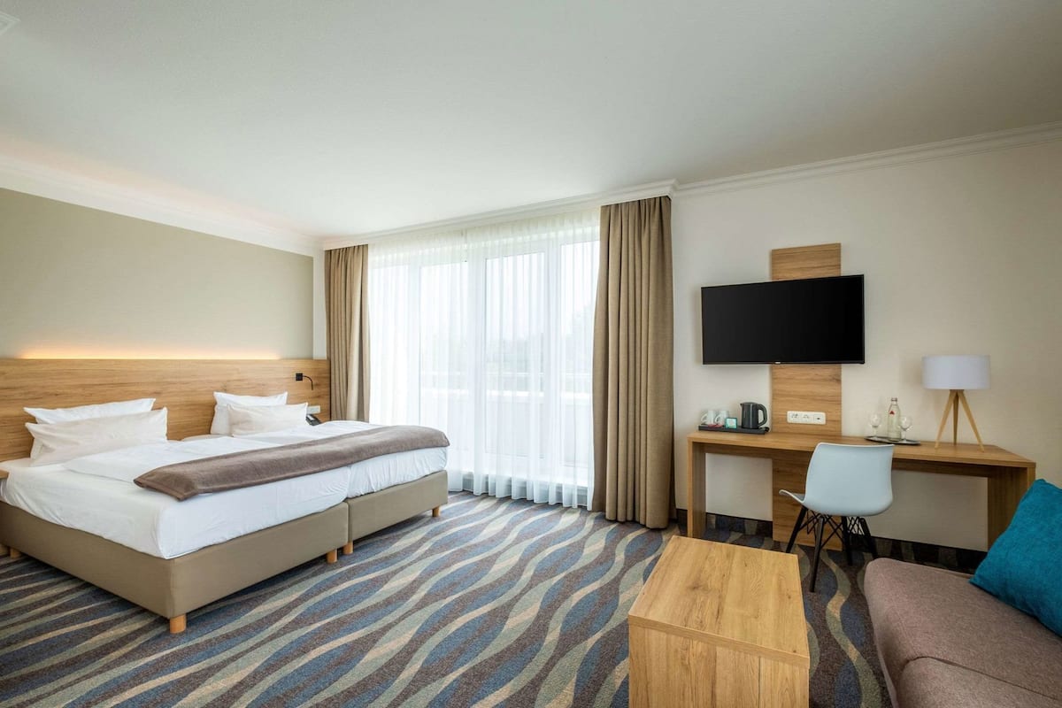 A hotel room with a bed, a desk, a television, and a sofa.