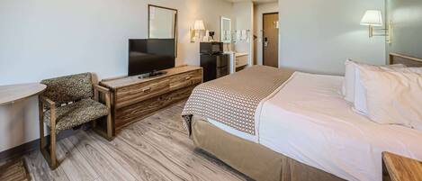 A hotel room with a bed, a TV, a desk, a chair, and a ceiling fan.