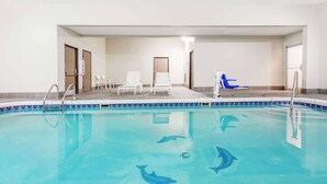 An indoor swimming pool with clear blue water, dolphin-shaped tiles, and lounge chairs. - Travelodge by Wyndham Longmont (Longmont)