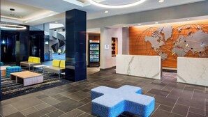 A modern lobby with a spiral staircase, seating areas, a reception desk, and a world map wall. - Sheraton Suites Philadelphia Airport (Philadelphia)