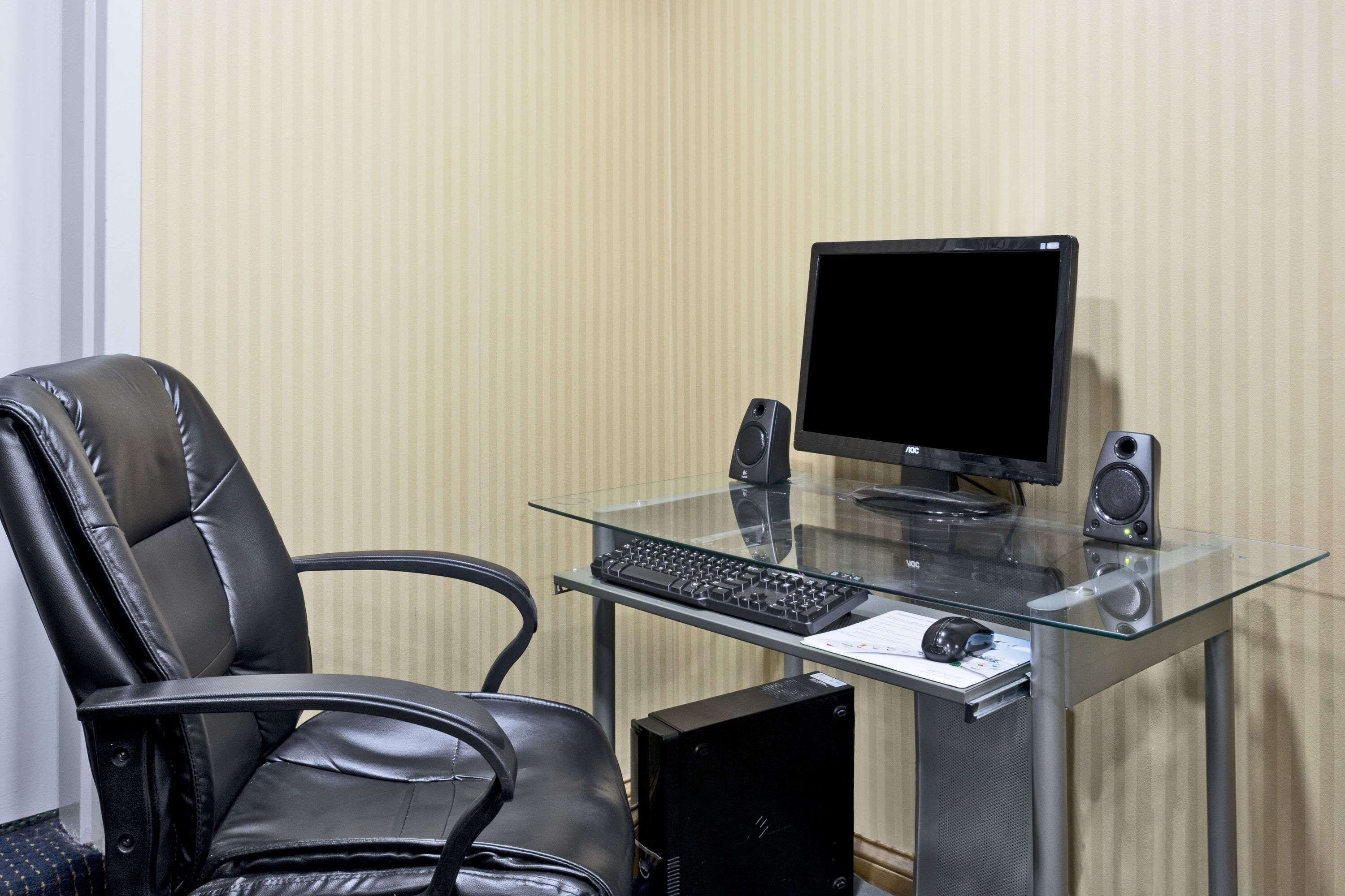 Un espacio de trabajo moderno con un escritorio de cristal, una silla de cuero, una computadora de escritorio y un teclado.