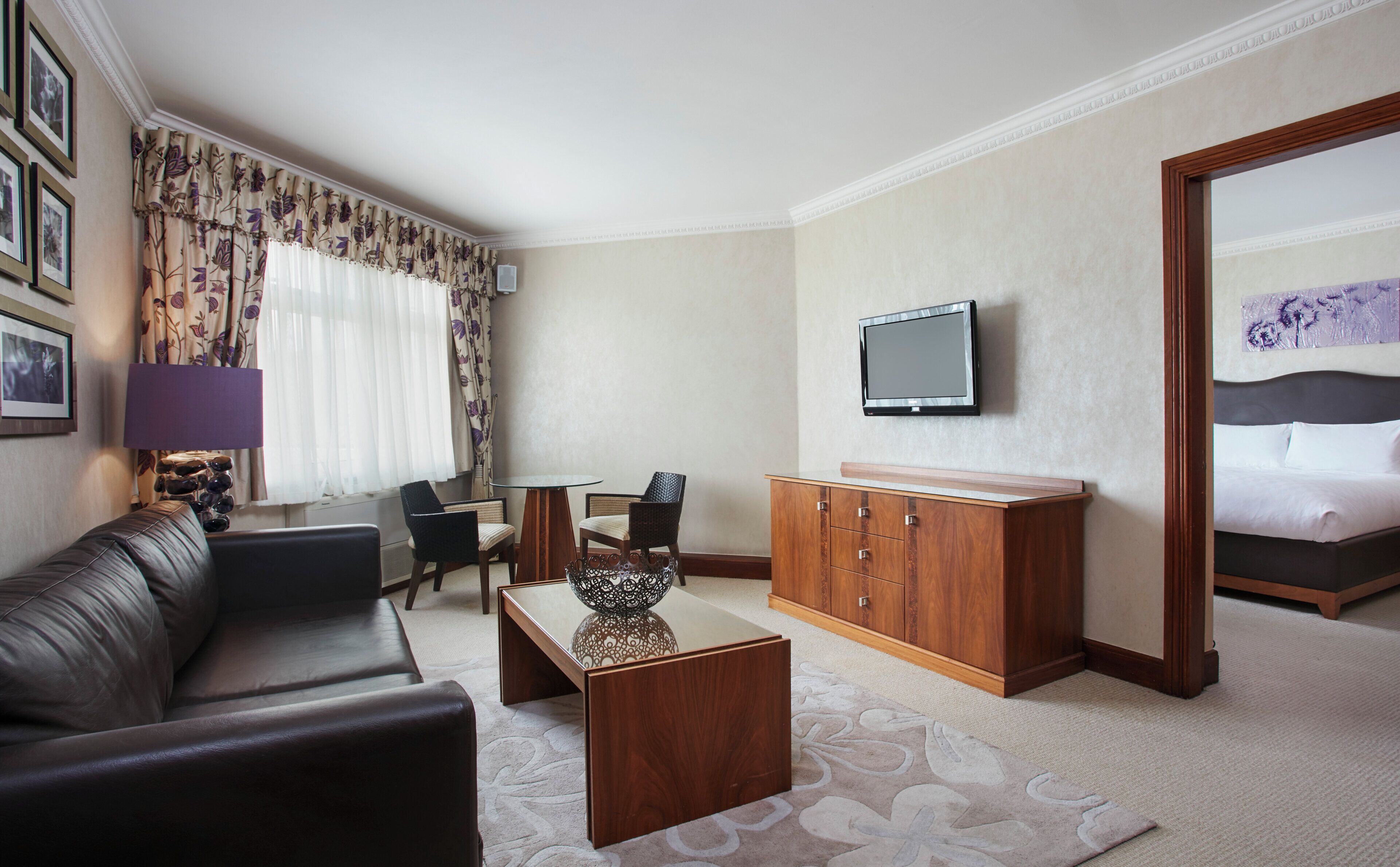 A hotel room with a sofa, a coffee table, a TV, a cabinet, and a bed.
