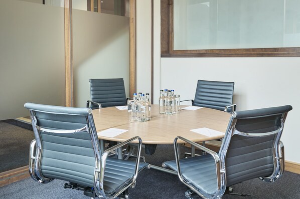 A conference room with a round table, four chairs, and water bottles.