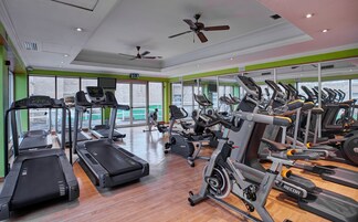Un gimnasio con cintas de correr, bicicletas estáticas y máquinas elípticas.