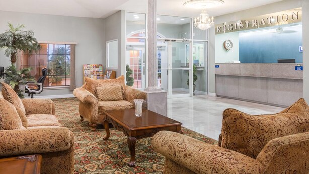 A lobby with patterned sofas, a wooden coffee table, and a reception desk labeled "REGISTRATION". - Days Inn by Wyndham Portland/Corpus Christi (Portland)