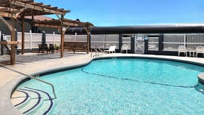 A swimming pool with a wooden pergola and white chairs around it. - Days Inn by Wyndham Portland/Corpus Christi (Portland)