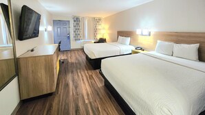 A hotel room with two beds, a desk, a chair, a TV, and a door. - Days Inn by Wyndham Portland/Corpus Christi (Portland)