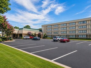 A hotel with a parking lot, a building with a green roof, and pink flowering trees. - Gardentree Hotels Memphis East near I 40 (Memphis)