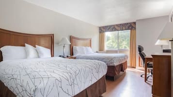 A hotel room with two beds, a desk, a chair, and a window with curtains.