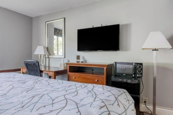 Une chambre d’hôtel équipée d’un lit, d’un bureau, d’une télévision, d’une lampe et d’un four à micro-ondes.