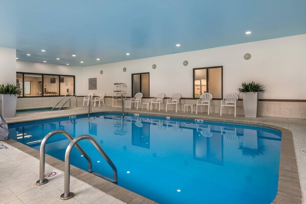 An indoor swimming pool with clear blue water, surrounded by white chairs and a tiled deck. - Comfort Inn & Suites Green Bay Stadium Area (Green Bay)