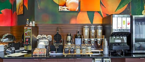 A kitchen area with a coffee machine, a waffle maker, and various containers.