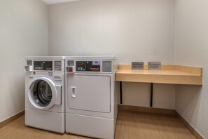 Een wasserette met een voorlader wasmachine en droger, bedieningsinstructies en wasprogramma tijdsduren.