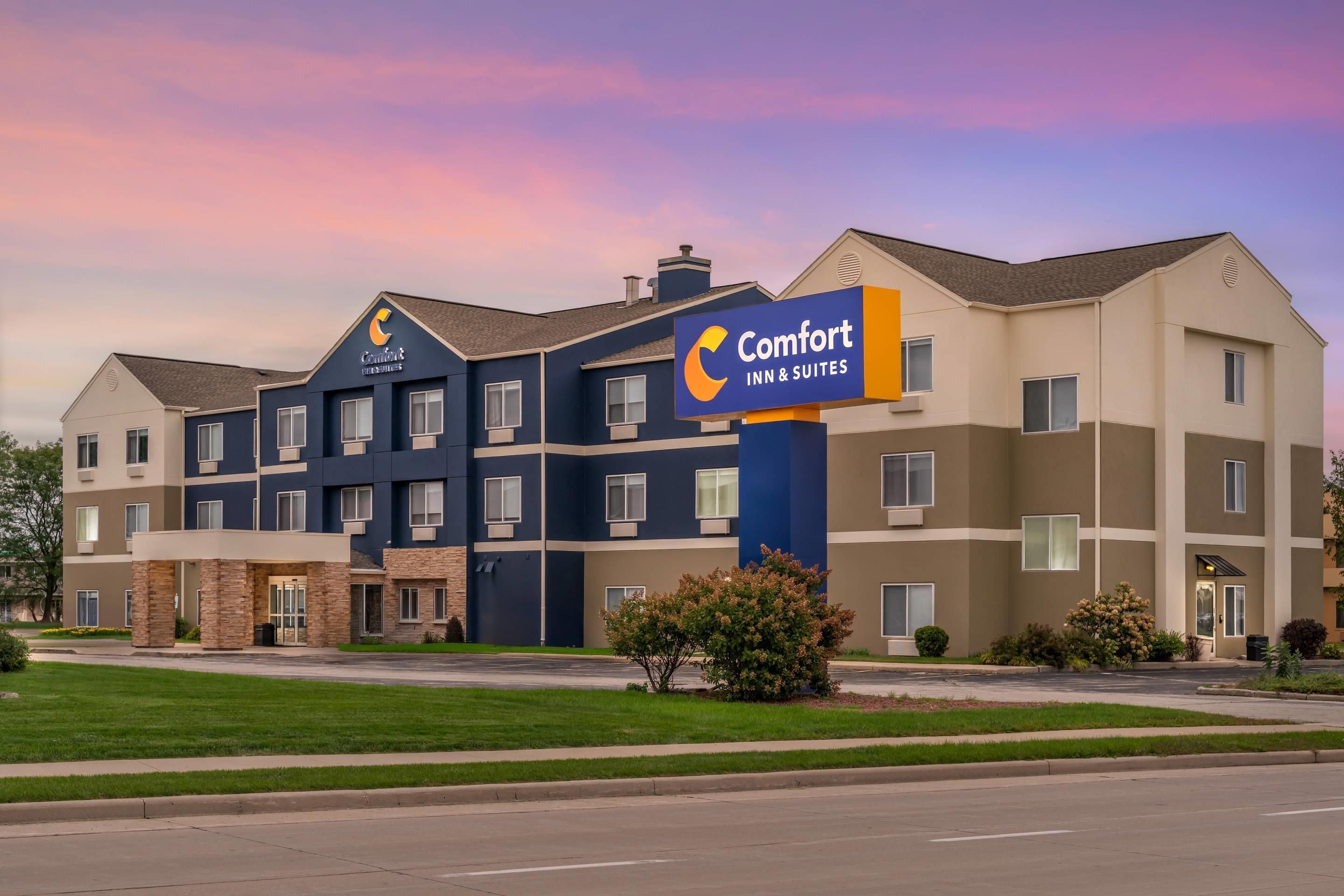 Un hotel Comfort Inn & Suites de varios pisos con un diseño arquitectónico moderno, destacando una señalización llamativa y un césped bien cuidado.