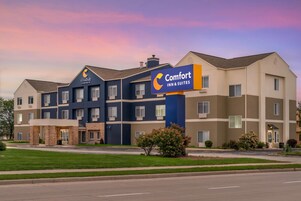 Un hotel Comfort Inn & Suites de varios pisos con un diseño arquitectónico moderno, destacando una señalización llamativa y un césped bien cuidado.