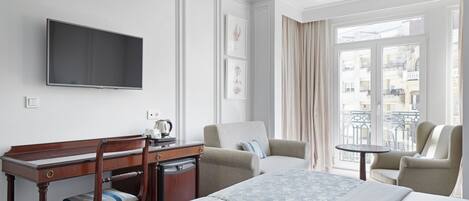 A hotel room with a bed, a desk, a chair, a television, and a balcony with curtains.