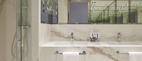 Une salle de bain moderne dotée d’une douche à parois de verre, de deux lavabos et d’un grand miroir.