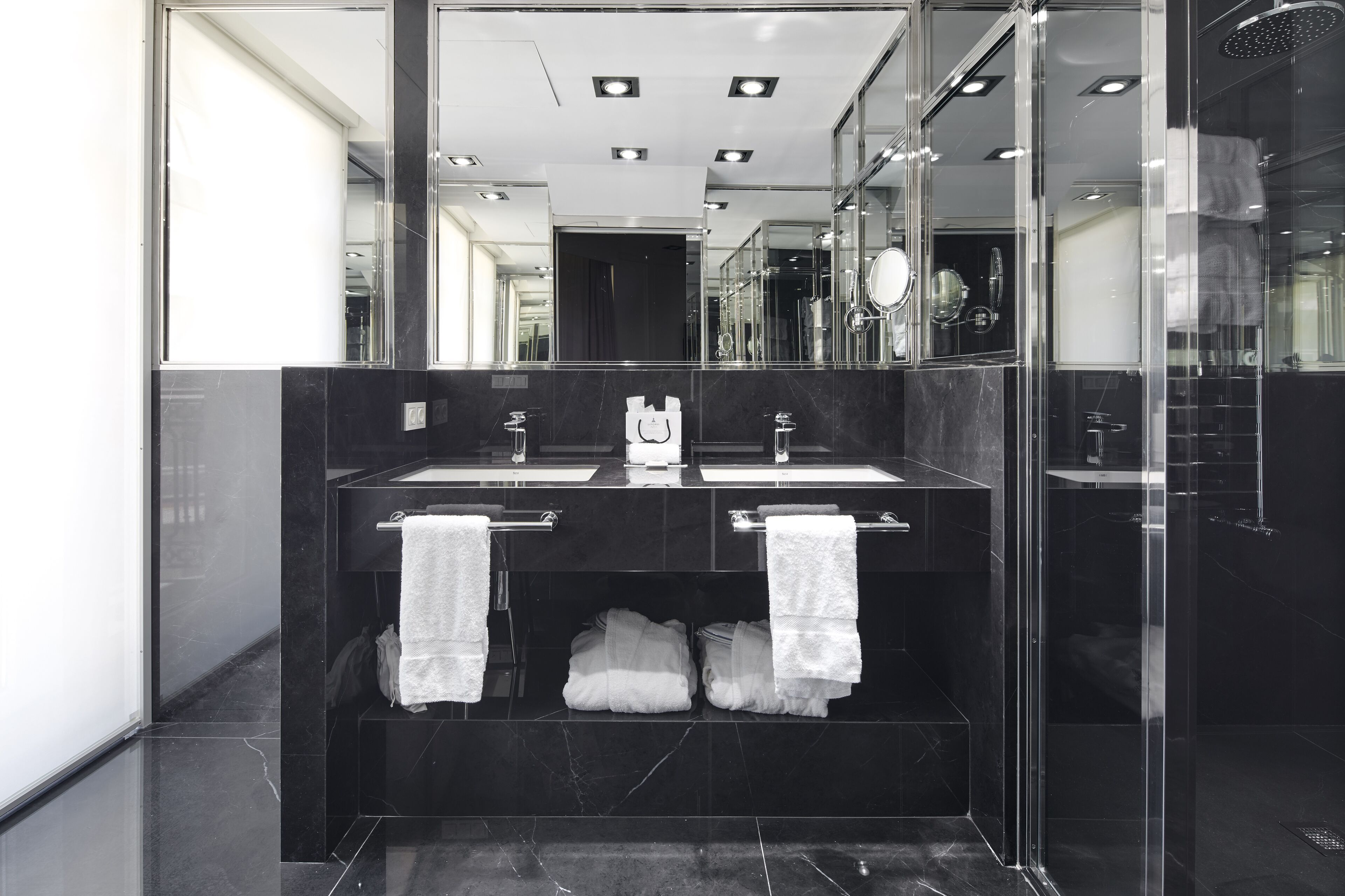 A modern bathroom with two sinks, a large mirror, and a glass shower enclosure.