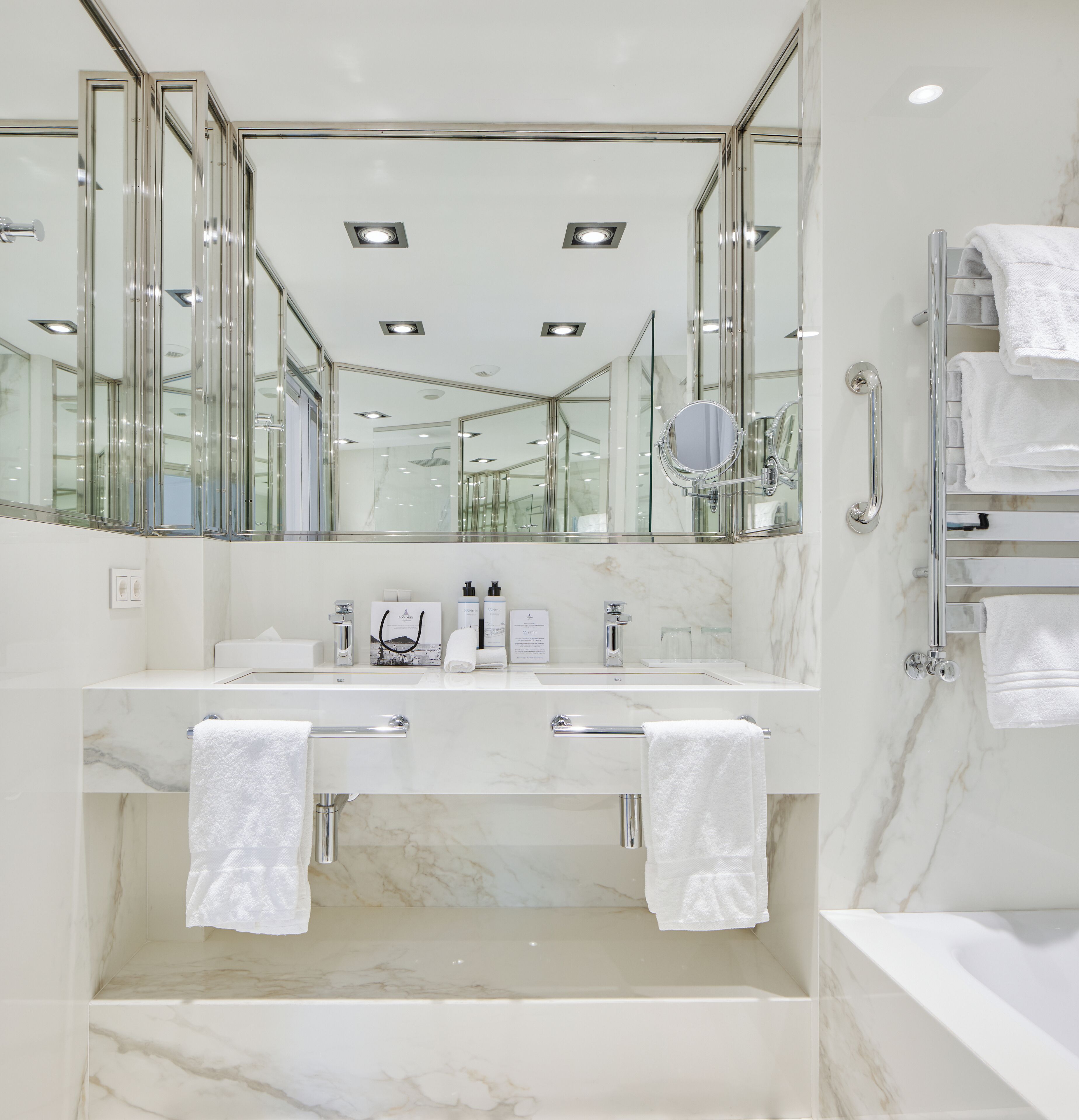 Un bagno moderno con un grande specchio, due lavabi e un piano di marmo.