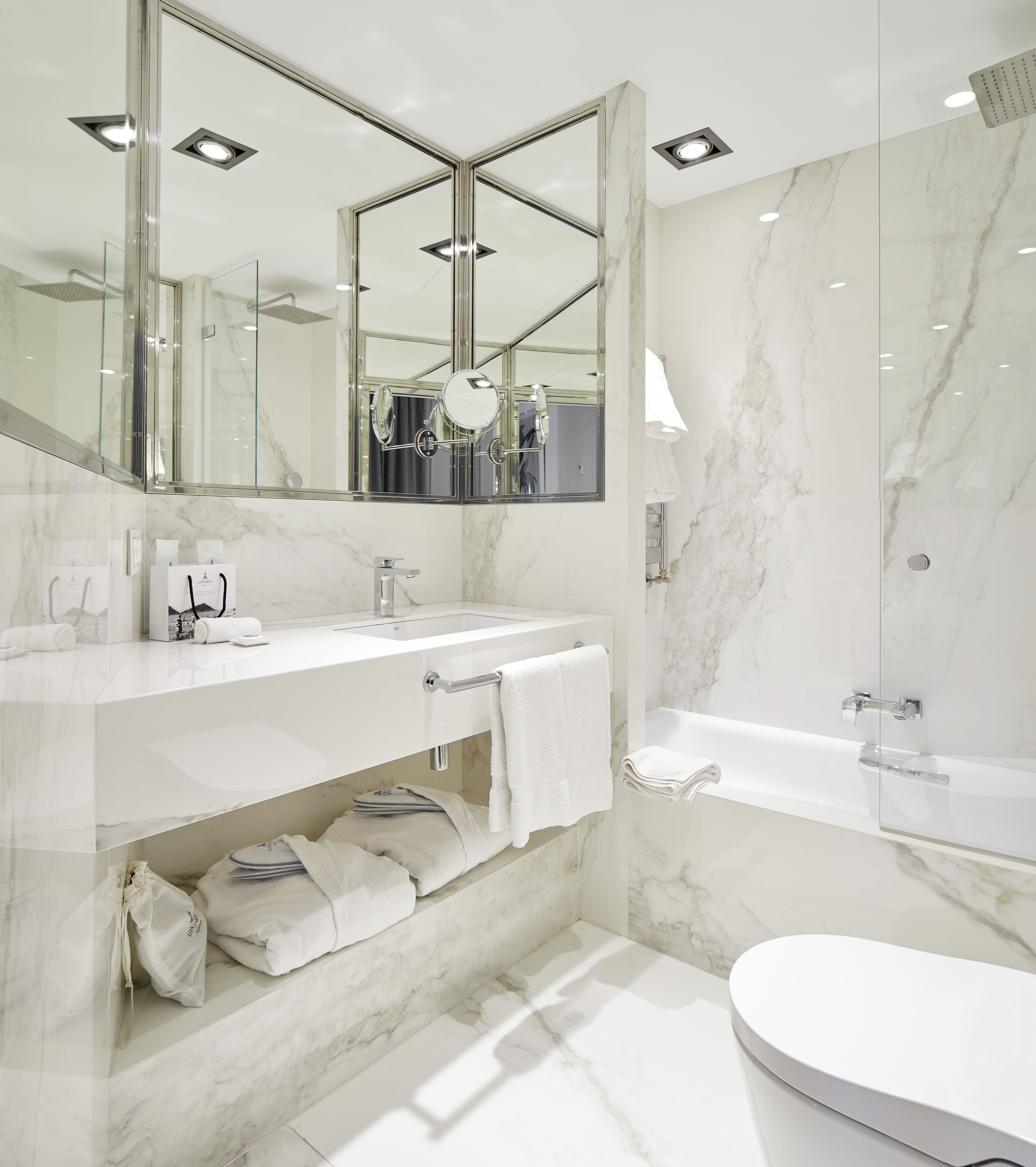 Une salle de bain moderne avec un grand miroir, un lavabo, une baignoire et des toilettes.
