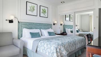 A hotel room with a large bed, a sofa, a nightstand, and a mirror.
