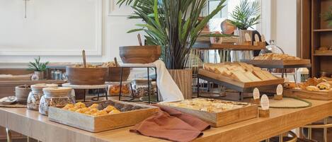 A buffet setup with various food items and a large potted plant.