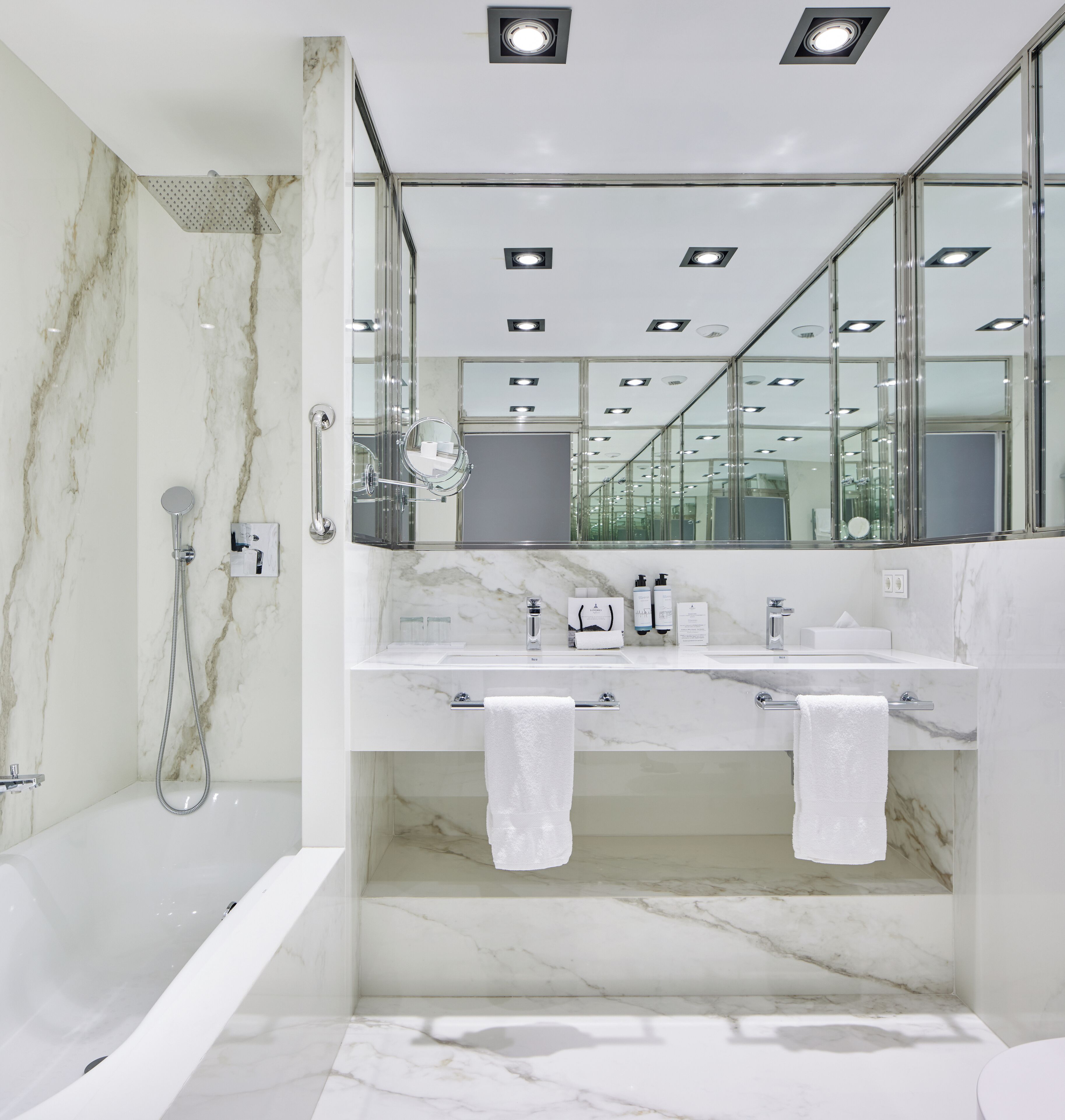 A modern bathroom with a marble vanity, dual sinks, a large mirror, and a walk-in shower.
