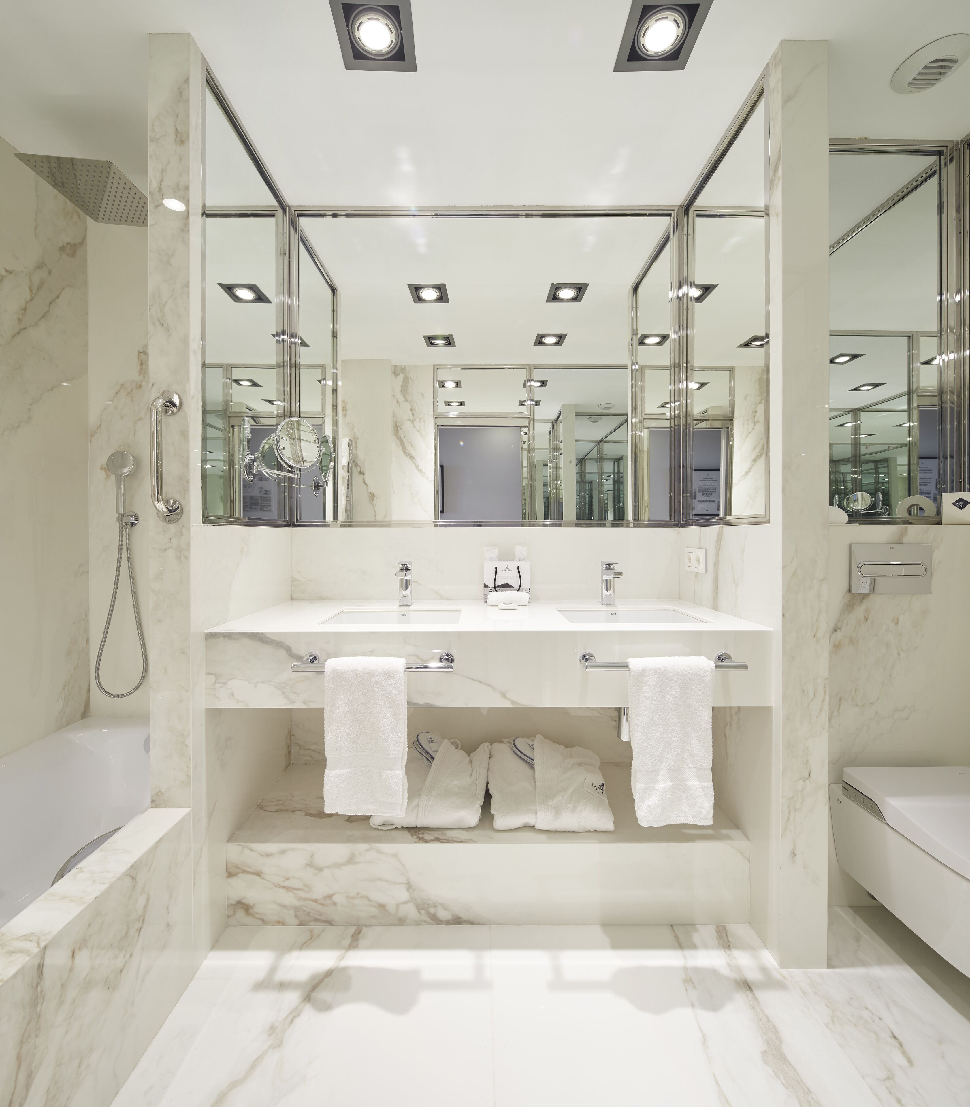 A modern bathroom with a marble vanity, a bathtub, and a shower.