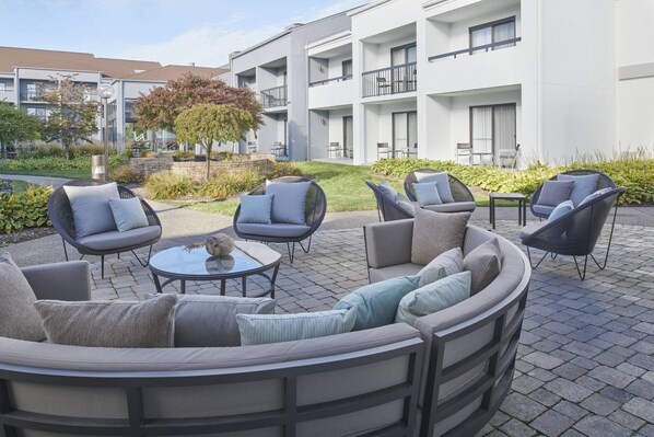 Relax in a serene outdoor seating area surrounded by lush greenery and comfortable seating.