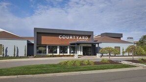 A modern Courtyard by Marriott hotel with a flat roof, large windows, and a well-maintained lawn. - Courtyard by Marriott Detroit Troy (Troy)