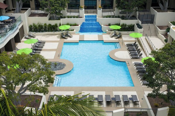 A rooftop pool with multiple levels of seating and a central water feature.
