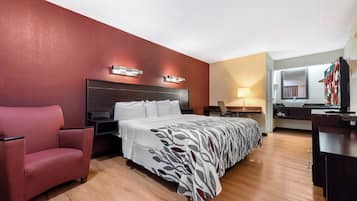 Une chambre d’hôtel comprenant un lit, un bureau, une chaise, un miroir et une salle de bain.