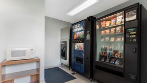 A vending machine area with a microwave on a shelf, a cold drinks machine, and a snack vending machine. - Red Roof Inn Lafayette - Purdue University (Lafayette)