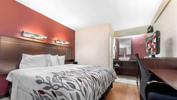 Une chambre d’hôtel équipée d’un lit, d’un bureau, d’une chaise, d’un miroir et d’un téléviseur.