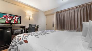 Een hotelkamer met een bed, een bureau, een televisie en een deur.