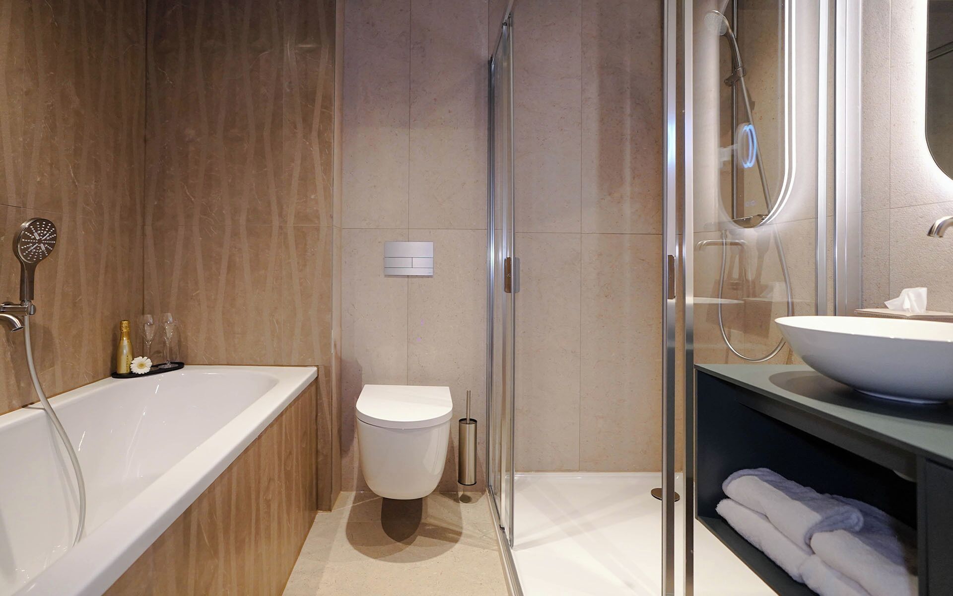 A modern bathroom with a glass shower enclosure, a standalone bathtub, a toilet, and a vanity with a large sink.
