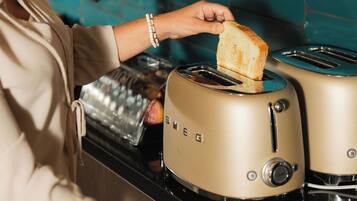 A person toasting bread on a kitchen stove with a toaster.